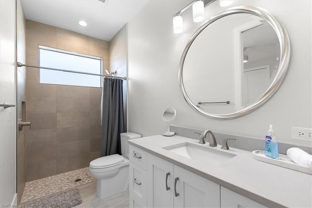 734 109th Avenue North Naples, FL 34108 - Photo 21 of 34 a bathroom with a sink a toilet and a mirror