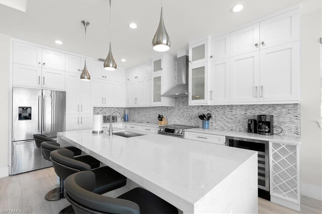 734 109th Avenue North Naples, FL 34108 - Photo 3 of 34 a kitchen with stainless steel appliances a sink a stove a refrigerator and white cabinets with wooden floor