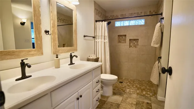 a bathroom with a sink a toilet a mirror and shower