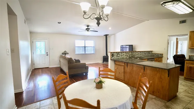 a open kitchen with stainless steel appliances granite countertop a sink a stove a dining table and chairs