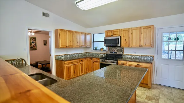 a kitchen with granite countertop a stove a sink and a microwave