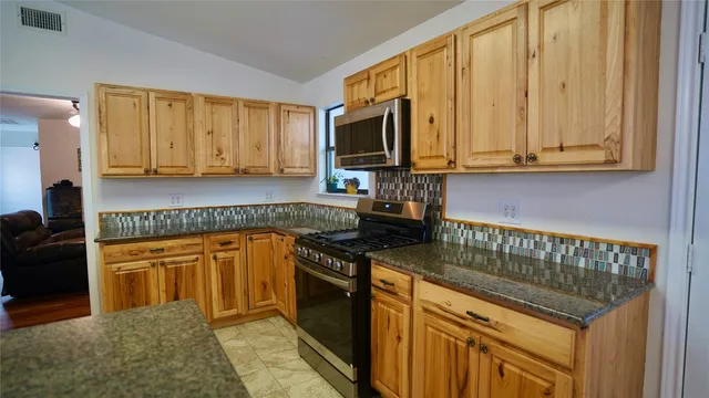 a kitchen with stainless steel appliances granite countertop a stove a sink and a microwave