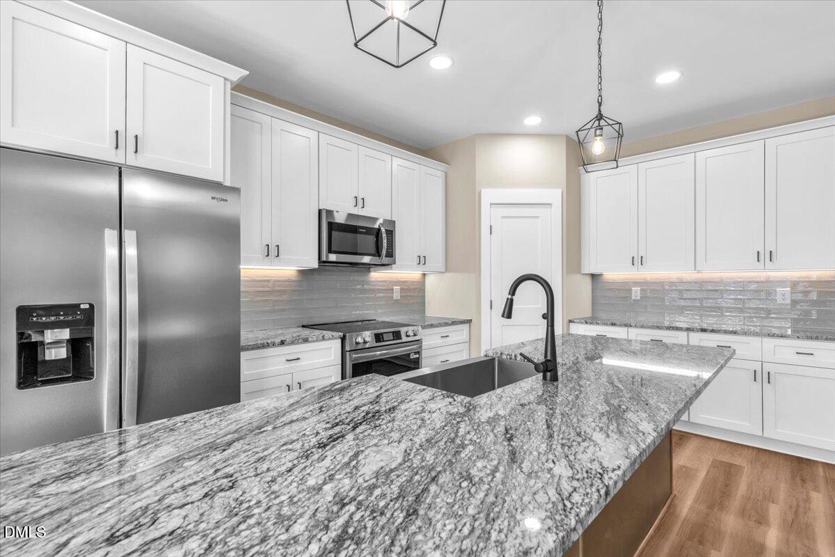 12615 Mallard Rock Drive Zebulon, NC 27597 - Photo 13 of 89 a kitchen with stainless steel appliances granite countertop a refrigerator a sink a stove and white cabinets with wooden floor