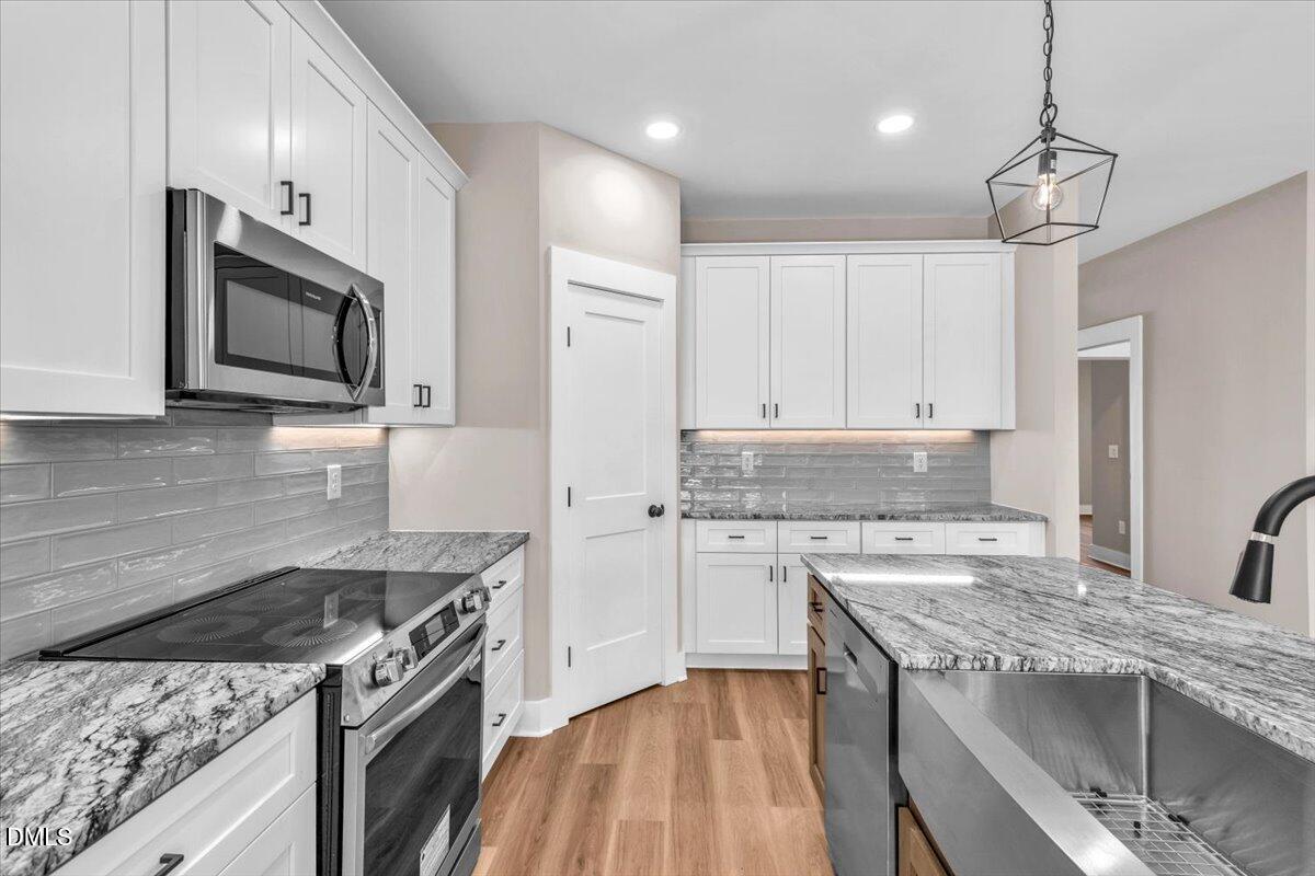 12615 Mallard Rock Drive Zebulon, NC 27597 - Photo 14 of 89 a kitchen with stainless steel appliances granite countertop a stove top oven a sink dishwasher and a microwave oven with large wooden cabinets