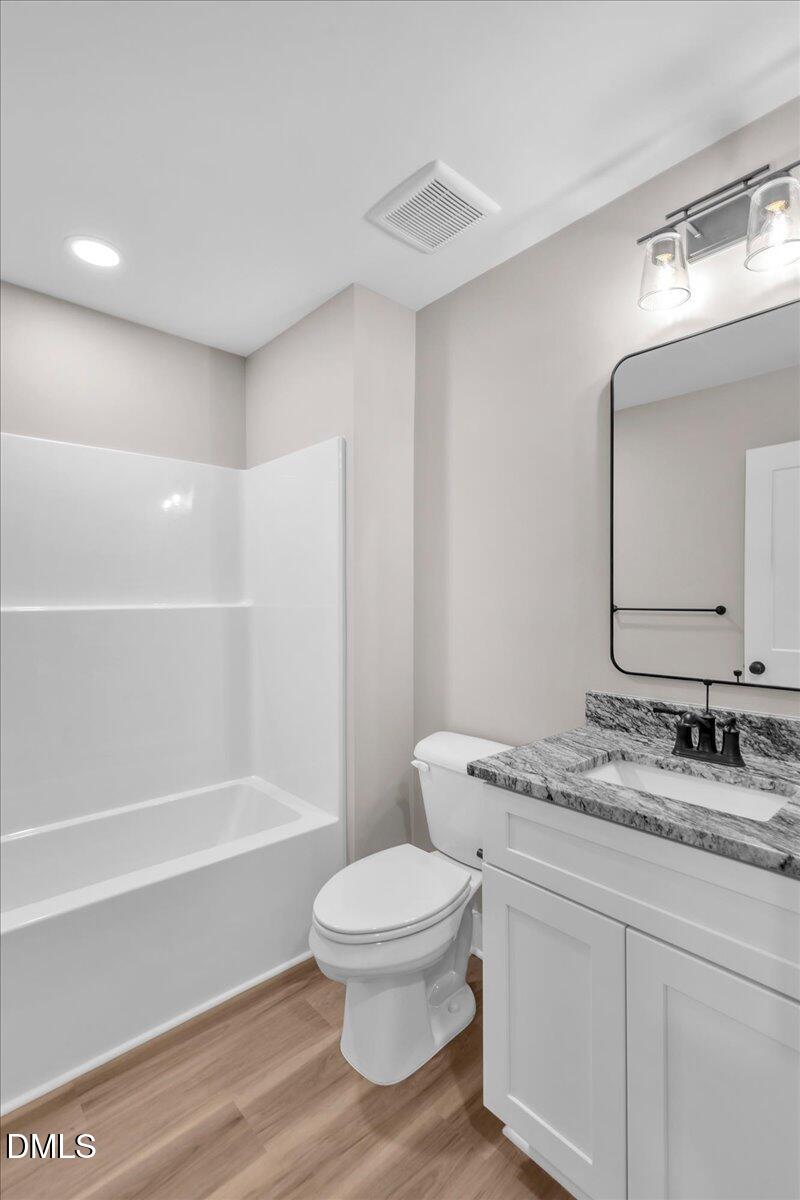12615 Mallard Rock Drive Zebulon, NC 27597 - Photo 71 of 89 a bathroom with a granite countertop toilet a sink and a mirror