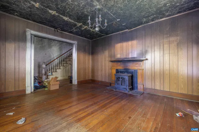 a view of an empty room with wooden floor fireplace and a window