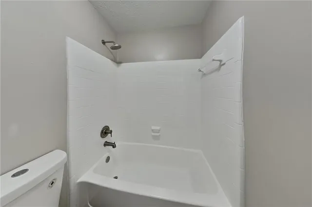 a white bath tub sitting next to a white toilet and vanity