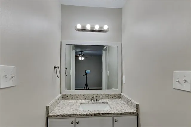 a bathroom with a granite countertop sink and a mirror