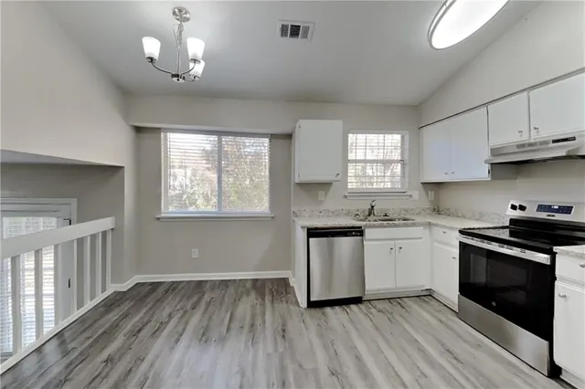 a kitchen with granite countertop wooden floors a sink stainless steel appliances and window