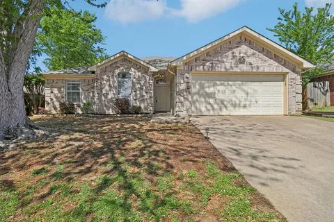 a view of a large house with a large tree and wooden fence