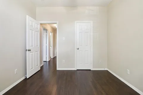 an empty room with wooden floor chandelier fan and windows