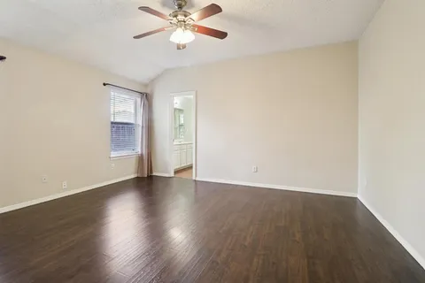 an empty room with wooden floor chandelier fan and windows
