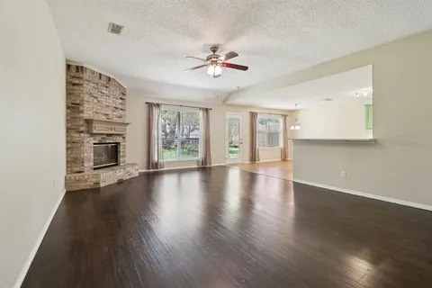 a view of a livingroom with wooden floor a ceiling fan and windows