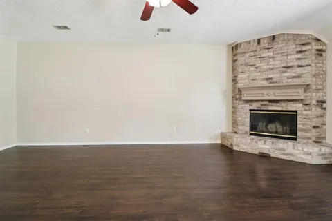 a view of an empty room with wooden floor fireplace and a window