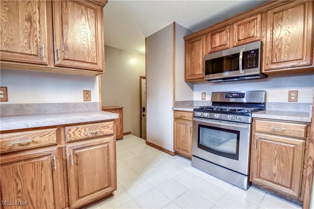 5618 Dolphin Road Mentor, OH 44060 - Photo 15 of 46 Kitchen featuring stainless steel appliances, light countertops, light tile patterned flooring, and brown cabinetry
