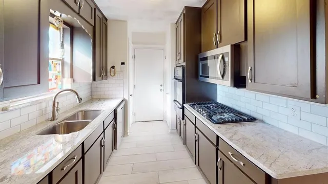 a kitchen with stainless steel appliances granite countertop a sink stove and refrigerator