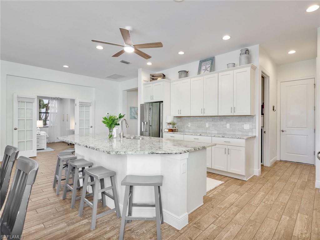 4743 Abaca Circle Naples, FL 34119 - Photo 14 of 50 Kitchen with light wood finished floors, white cabinets, a breakfast bar area, and recessed lighting