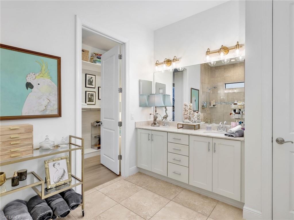 4743 Abaca Circle Naples, FL 34119 - Photo 26 of 50 Full bathroom featuring a tile shower, light tile patterned floors, and double vanity