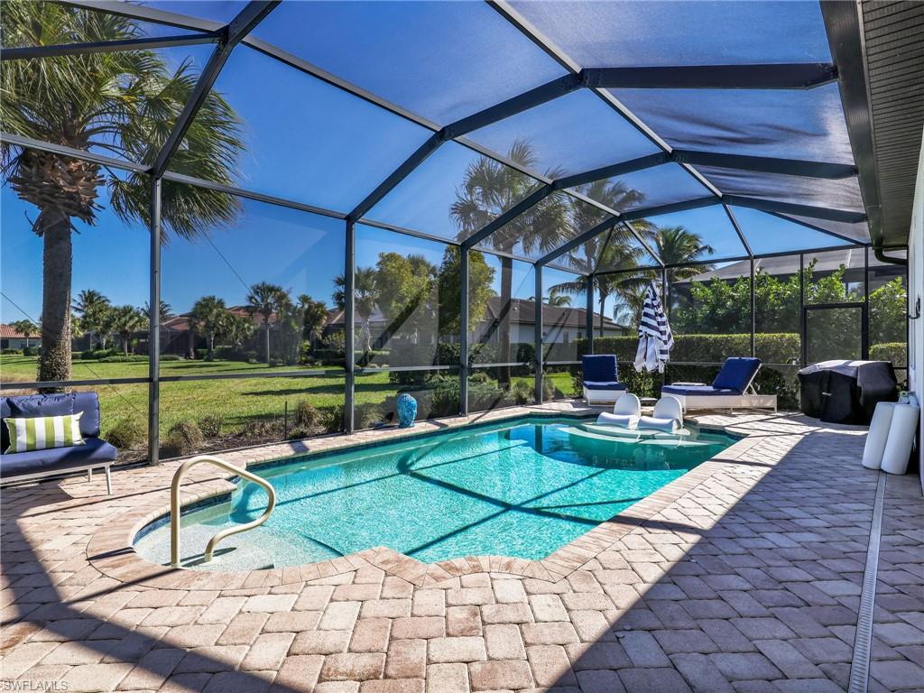 4743 Abaca Circle Naples, FL 34119 - Photo 39 of 50 Outdoor pool featuring glass enclosure, a sunroom, a patio area, and a lawn