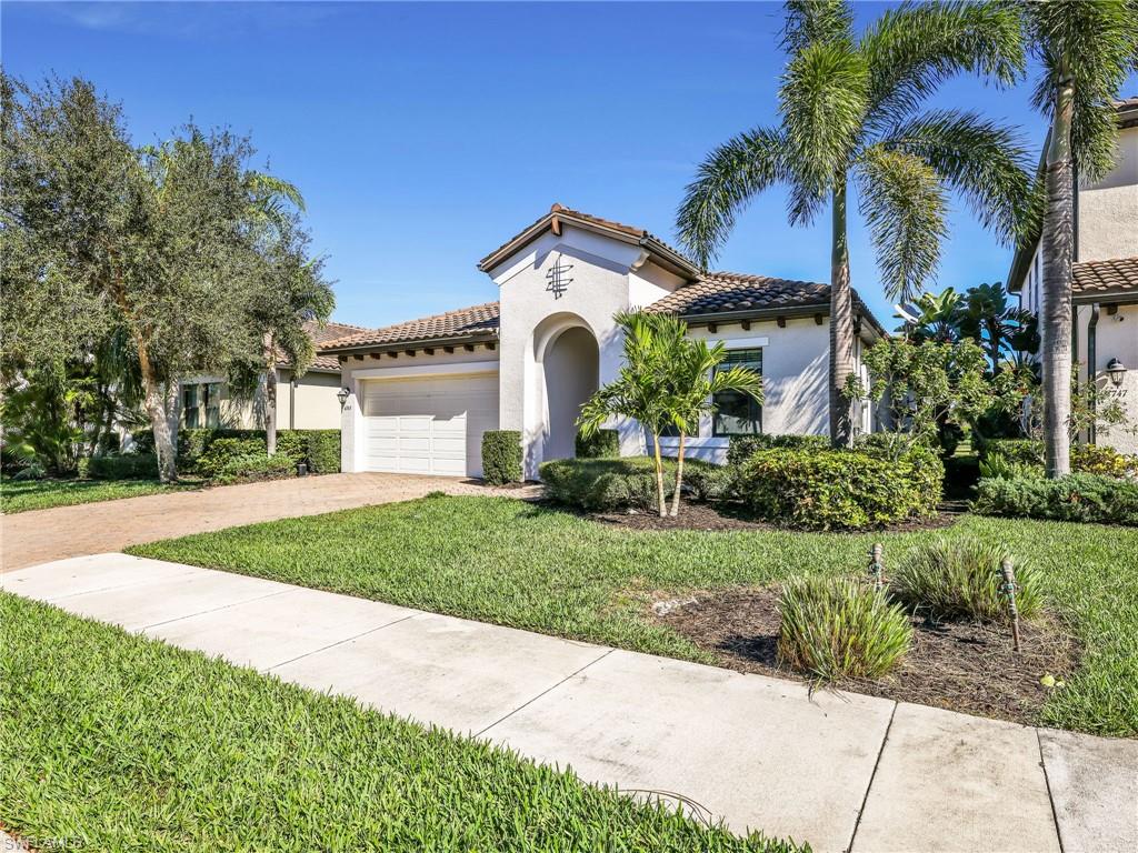 4743 Abaca Circle Naples, FL 34119 - Photo 7 of 50 Mediterranean / spanish-style house featuring a front lawn, stucco siding, an attached garage, and a tile roof