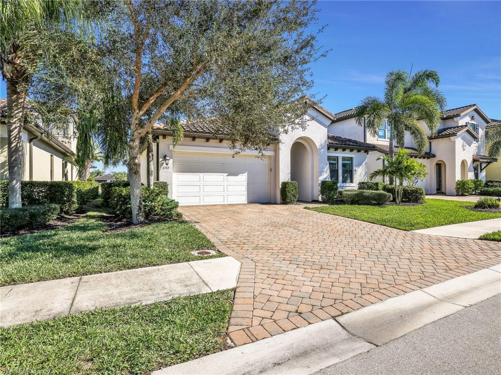 4743 Abaca Circle Naples, FL 34119 - Photo 8 of 50 Mediterranean / spanish-style house featuring decorative driveway, stucco siding, a front lawn, a garage, and a tiled roof