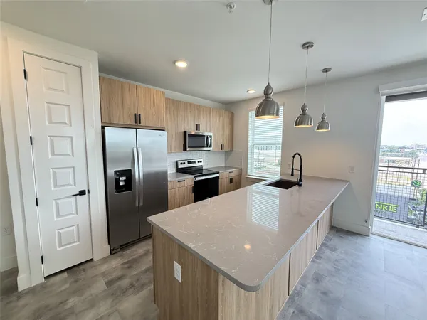 a kitchen with stainless steel appliances granite countertop a refrigerator a sink dishwasher a oven with white cabinets and wooden floor