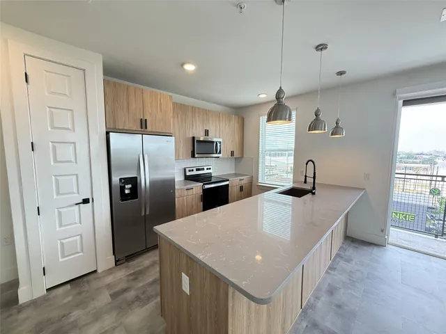 a kitchen with stainless steel appliances granite countertop a refrigerator a sink dishwasher a oven with white cabinets and wooden floor