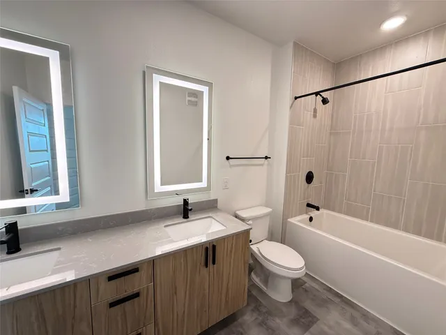 a bathroom with a double vanity sink toilet mirror and bathtub