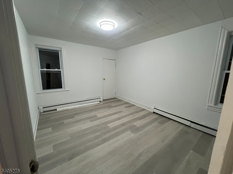 12 Quincy Street, Unit 1 Passaic, NJ 07055 - Photo 2 of 16 a view of an empty room with wooden floor and a window