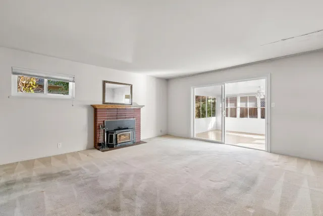 a view of an empty room with a fireplace and a window