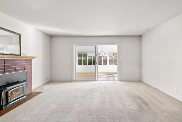 a view of an empty room with a fireplace and a window