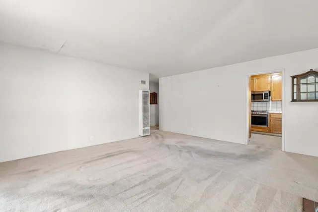 a view of empty room with kitchen and window