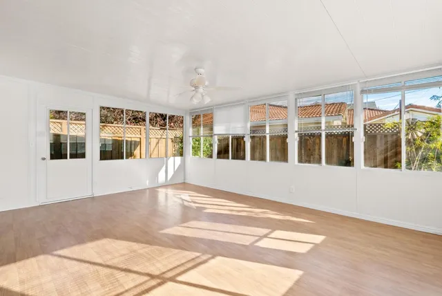 a view of an empty room with wooden floor and windows
