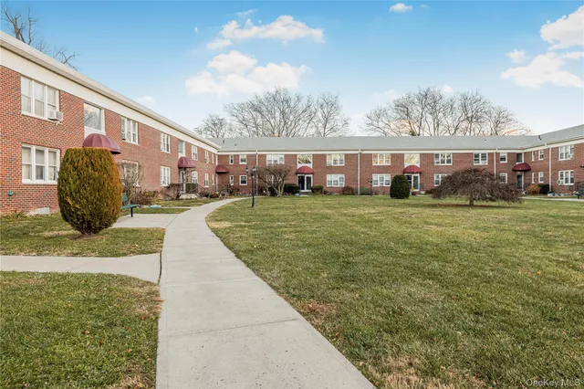 a view of a white house next to a yard with big trees