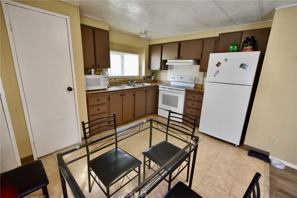 14804 Oregon Road Hornbrook, CA 96044 - Photo 11 of 26 a kitchen with a refrigerator a stove top oven a sink and white cabinets