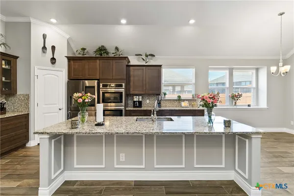 a view of kitchen with stainless steel appliances granite countertop a refrigerator and microwave