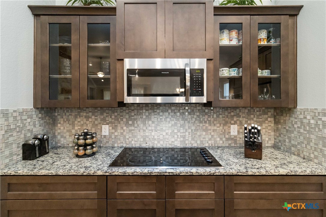 8402 Ridge Crest Drive Killeen, TX 76542 - Photo 13 of 34 a kitchen with granite countertop a stove a microwave and cabinets