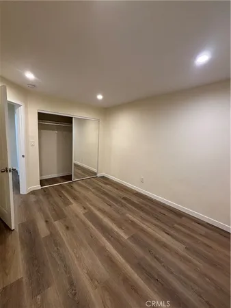 a view of an empty room with wooden floor and closet