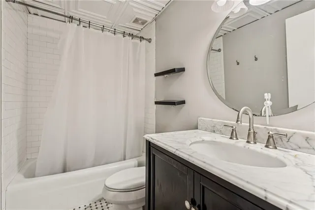 a bathroom with a granite countertop sink toilet and a mirror