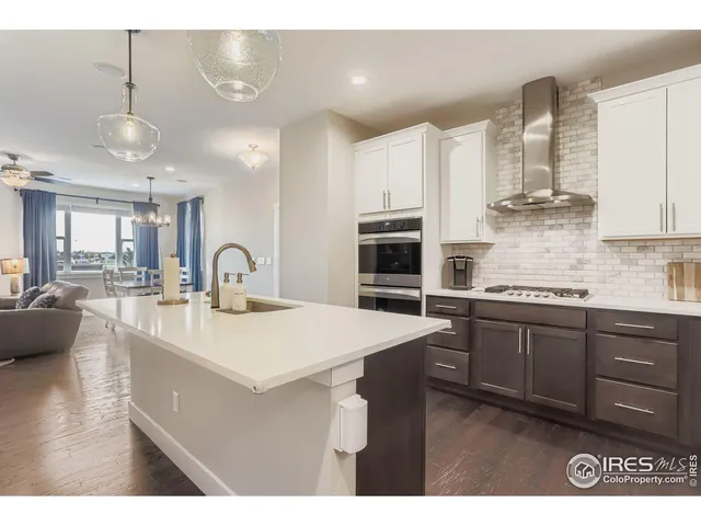 a kitchen with stainless steel appliances kitchen island granite countertop a sink a stove and a wooden floors