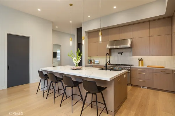 a kitchen with stainless steel appliances granite countertop a sink a stove a refrigerator and island with wooden floor