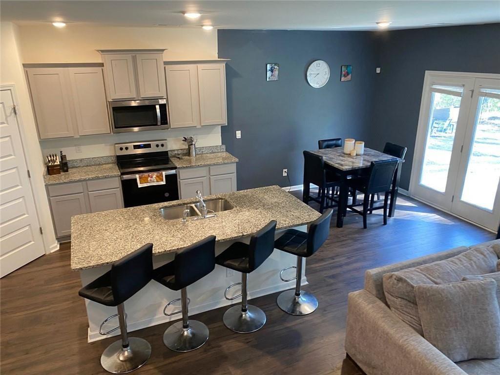 676 Whitman Lane Stockbridge, GA 30281 - Photo 5 of 50 a kitchen with stainless steel appliances granite countertop a sink a stove a dining table and chairs with wooden floor