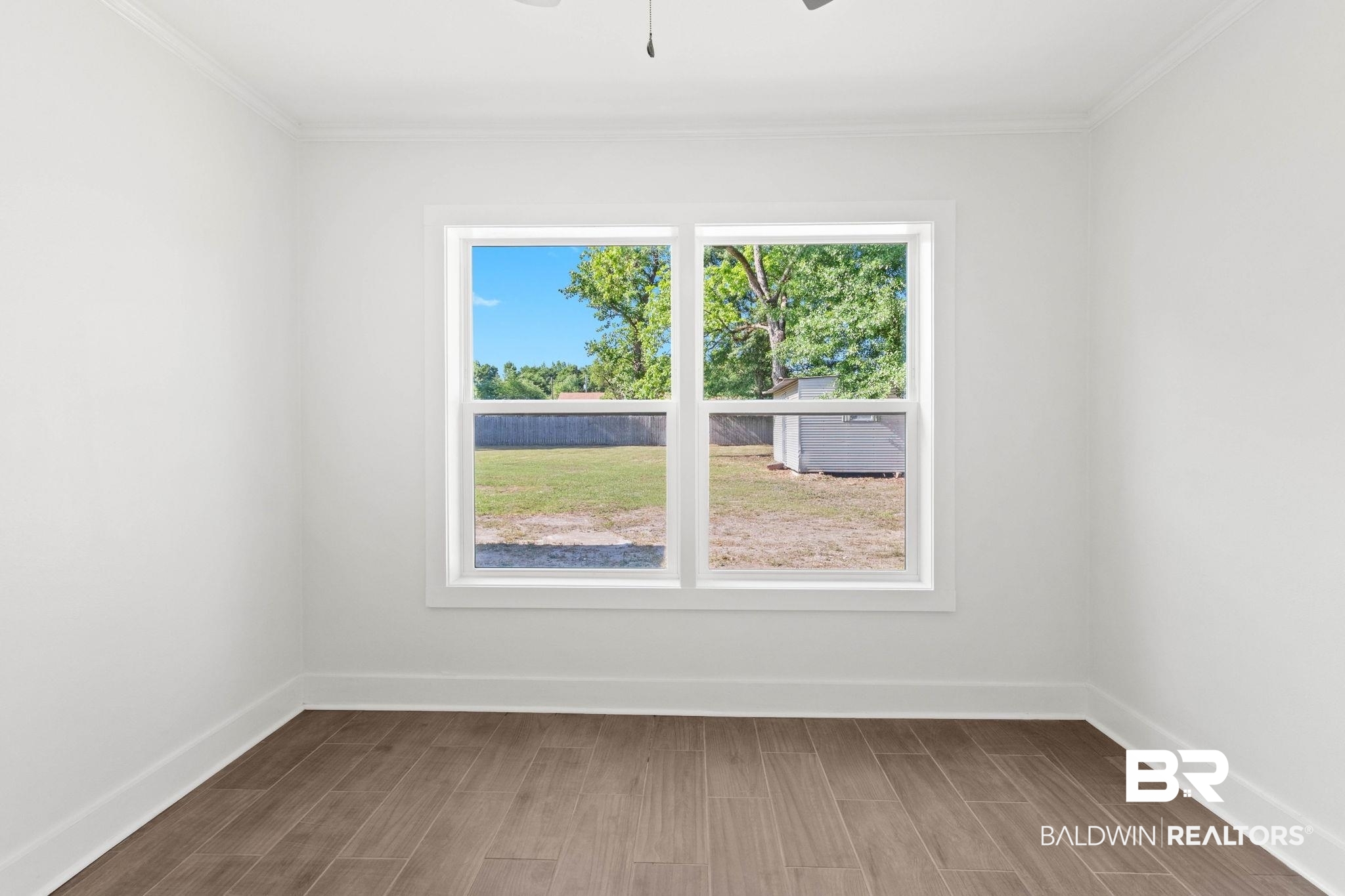 311 Cloverdale Road Atmore, AL 36502 - Photo 39 of 63 Bright interior space featuring a large window, wood-finish flooring, white walls, white trim, and crown molding