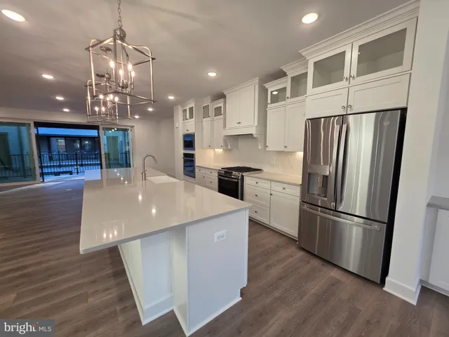 a kitchen with stainless steel appliances a refrigerator a sink dishwasher a stove and white cabinets with wooden floor