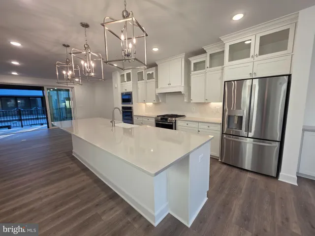 a view of a room with wooden floor kitchen view and a chandelier