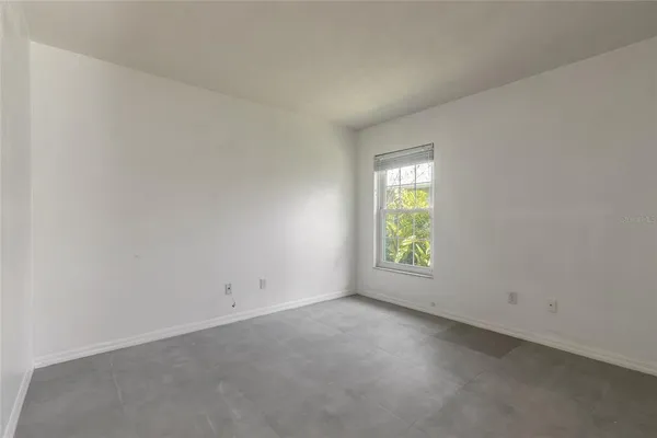 an empty room with a chandelier fan and windows