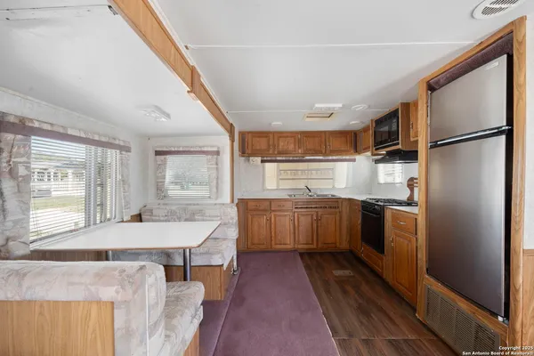 a kitchen with stainless steel appliances granite countertop a refrigerator a sink dishwasher a stove and a dining table with wooden floor