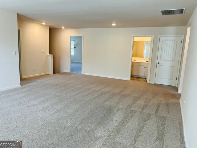 a view of an empty room with wooden floor and a bathroom
