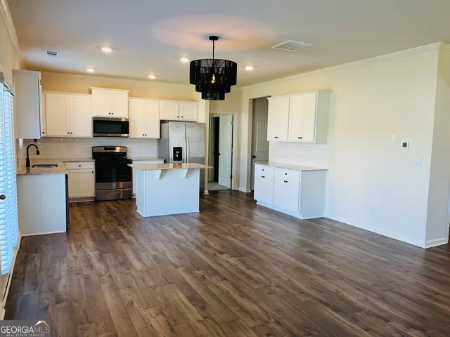 a living room with stainless steel appliances kitchen island wooden floors and fireplace