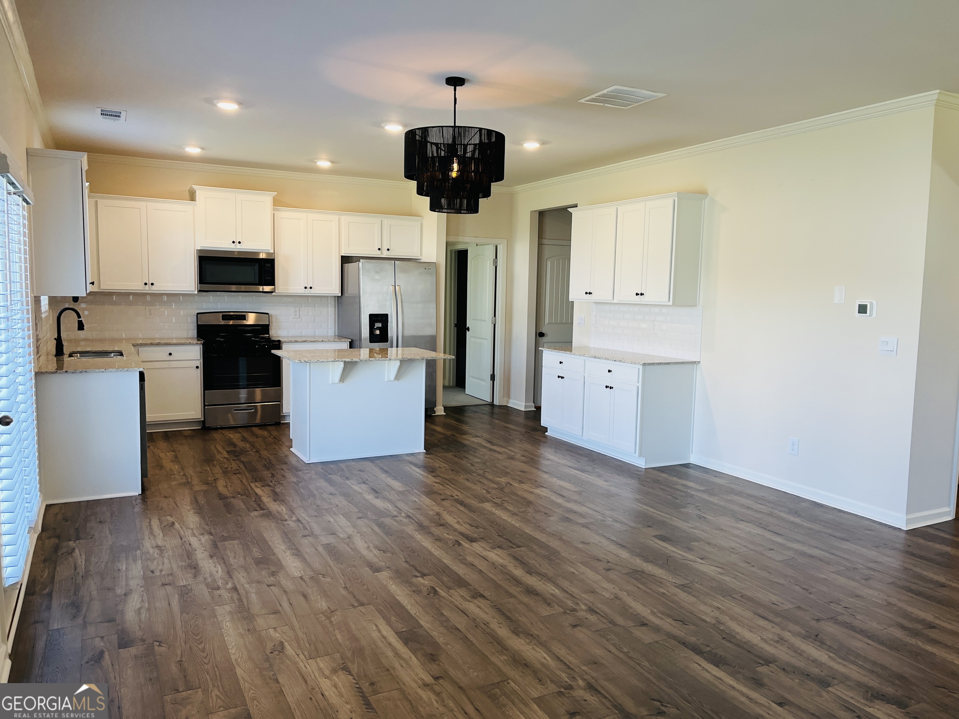 910 Sly Fox Run Fairburn, GA 30213 - Photo 9 of 46 a living room with stainless steel appliances kitchen island wooden floors and fireplace